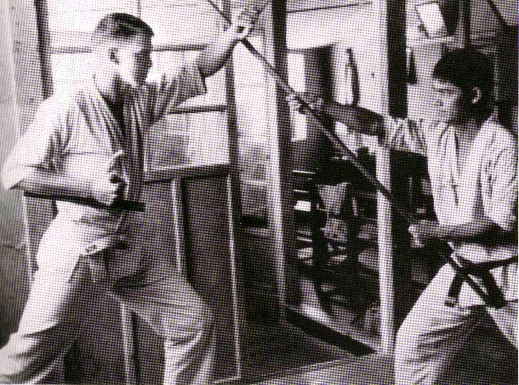 Master Ueshiro spars using his bo against an American serviceman wielding the tuifa